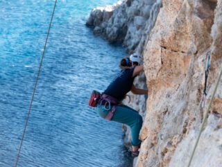 LHOer climbing over the sea on a remote beach only accessible by boat during the Rock Climbing in Kalymnos adventure with the Life Happens Outdoors team.