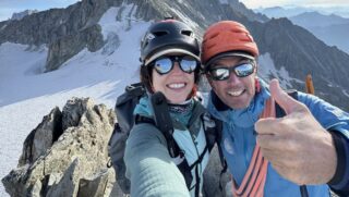 Nelly Attar and IFMGA guide François Xavier on the summit of Aiguille d'Entreves during the training and acclimatization portion of the Eiger course, with the Dent du Géant in the background and incredible views across the Glacier du Géant and the Vallée Blanche.