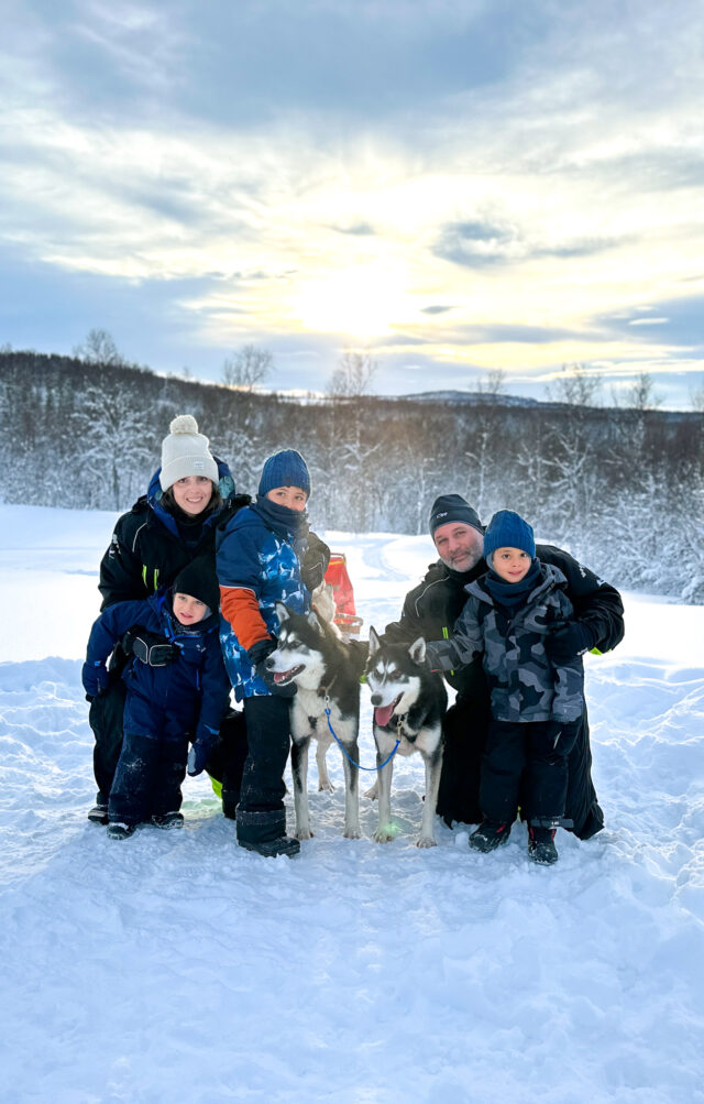 A family with young kids dog sledding during the Find Yourself Under the Northern Lights trip with the Life Happens Outdoors team.