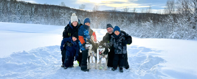 A family with young kids dog sledding during the Find Yourself Under the Northern Lights trip with the Life Happens Outdoors team.