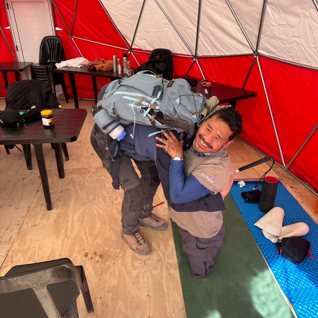 Hari Budha Magar, the first double over-the-knee amputee to climb Everest, and Frederik Sfeir, who has retinitis pigmentosa, meeting for the first time at Plaza de Mulas. Both are pushing through their unique challenges to achieve their aims—Hari's journey to complete the 7 Summits and Frederik’s determination to climb despite his visual impairment—during the Aconcagua Expedition with the Life Happens Outdoors team.