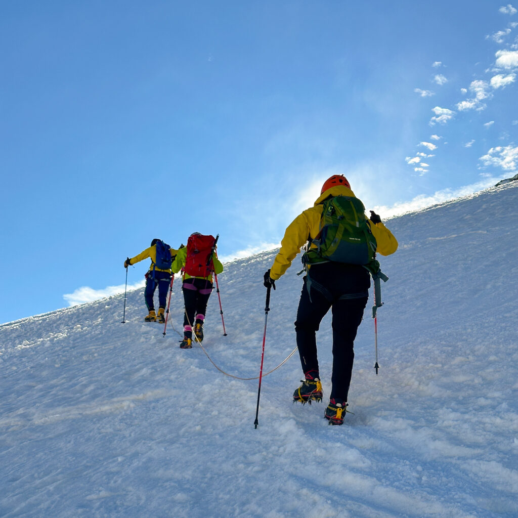 LHO Team ascending the third mogul on the Mont Blanc summit ridge during the Climb Mont Blanc Summit Course with glaciers in the background.