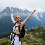 LHO team member at Col de Balme crossing from France into Switzerland on the Tour du Mont Blanc trail, with misty views over Chamonix Valley and a glacier in the background.