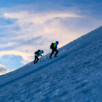 IFMGA guide Philippe Genin leading the first Emirati woman to summit Mont Blanc, Fatima Sajwani, on the first mogul of Mont Blanc at sunrise, with an incredible sky in the background during the Mont Blanc Summit Course with the Life Happens Outdoors team.