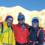 LHO guide Babis Marinidis on the summit of Petite Flambeau with Mont Blanc in the background during the Mont Blanc Summit Climb course with the Life Happens Outdoors team.