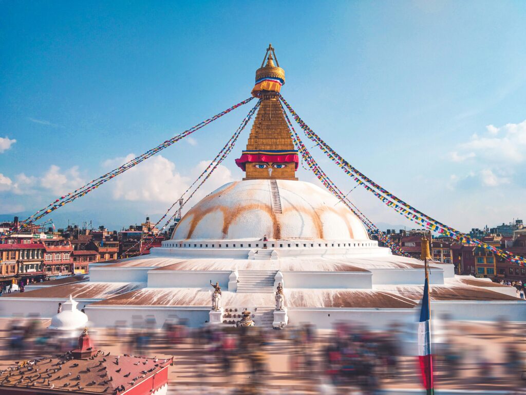 Boudhanath Stupa in Kathmandu Nepal with pedestrians bustling around it. 