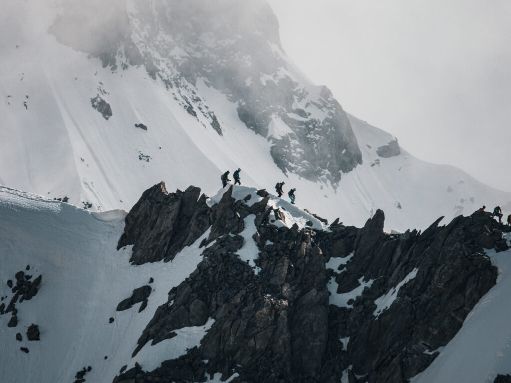 Climbers traversing the Marbrées ridge as seen from the Vallée Blanche with clouds parting to reveal the base of the Dent du Géant.