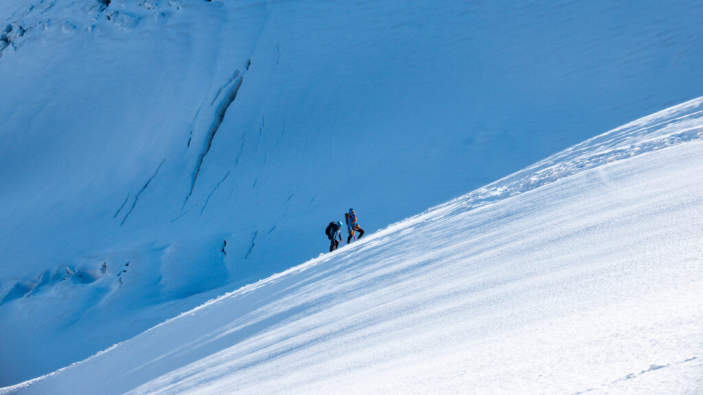 Climbers ascending glacier below Petit Flambeau during Mont Blanc Summit Course with panoramic view of the Vallée Blanche and surrounding peaks.