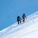 LHO IFMGA mountain guide leading climber on Petit Flambeau glacier during Mont Blanc Summit Course training with Vallee Blanche in background.