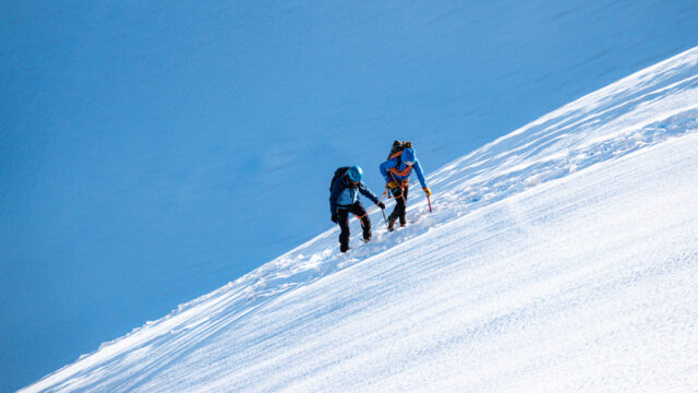 LHO IFMGA mountain guide leading climber on Petit Flambeau glacier during Mont Blanc Summit Course training with Vallee Blanche in background.