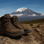 A tan waterproof hiking boot with durable laces and rugged tread sits on rocky terrain, ideal for climbing Mount Kilimanjaro in varied conditions.