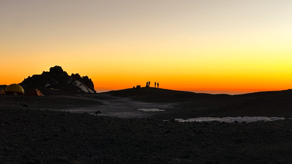 LHO team standing on a ridge at Camp 2 on Aconcagua, watching a stunning sunset over the Andes during their high altitude expedition.