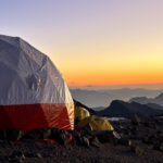 Dome tent at Aconcagua Camp 2 glowing under a golden sunset sky during a Life Happens Outdoors expedition on the Normal Route climb of Mount Aconcagua.