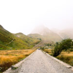 Hiker on the road to Col de la Seigne in Italy’s Val Veny, surrounded by mystical fog—an iconic section of the Tour du Mont Blanc trail.