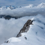 Life Happens Outdoors climbers ascending the Weissmies ridge with sweeping views of the Saas Valley and the dramatic peaks of the Mischabel range in the background