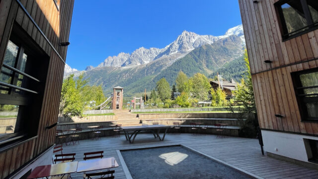 View of the Mont Blanc massif from the garden of RockyPop Hotel, with alpine peaks in the distance and outdoor seating in the foreground.
