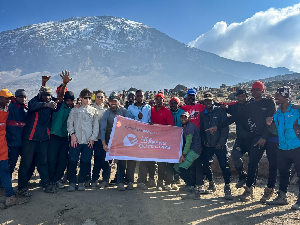 The entire Life Happens Outdoors team of porters, guides, and joiners gathered at Karanga Camp with Mount Kilimanjaro towering in the background.