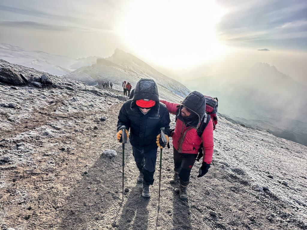 13-year-old Christopher Abboud moments before summiting Mount Kilimanjaro at sunrise with LHO veteran guide Saidi during expedition for HALO Trust.