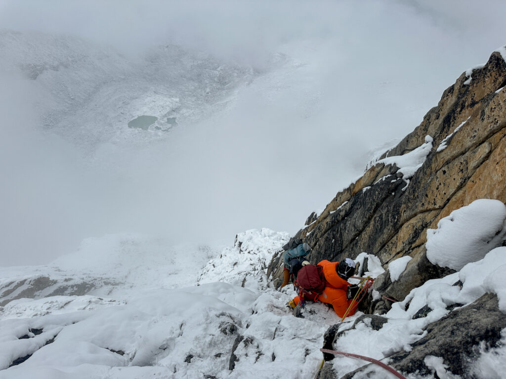 LHO climber descending the Yellow Tower on Ama Dablam in snowy conditions with technical gear and steep exposed Himalayan terrain in view.
