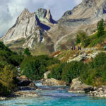 LHO group trekking through the stunning Val Veny section of the Tour du Mont Blanc, surrounded by dramatic Alpine peaks and lush green valleys, showcasing the difference between trekking and hiking.