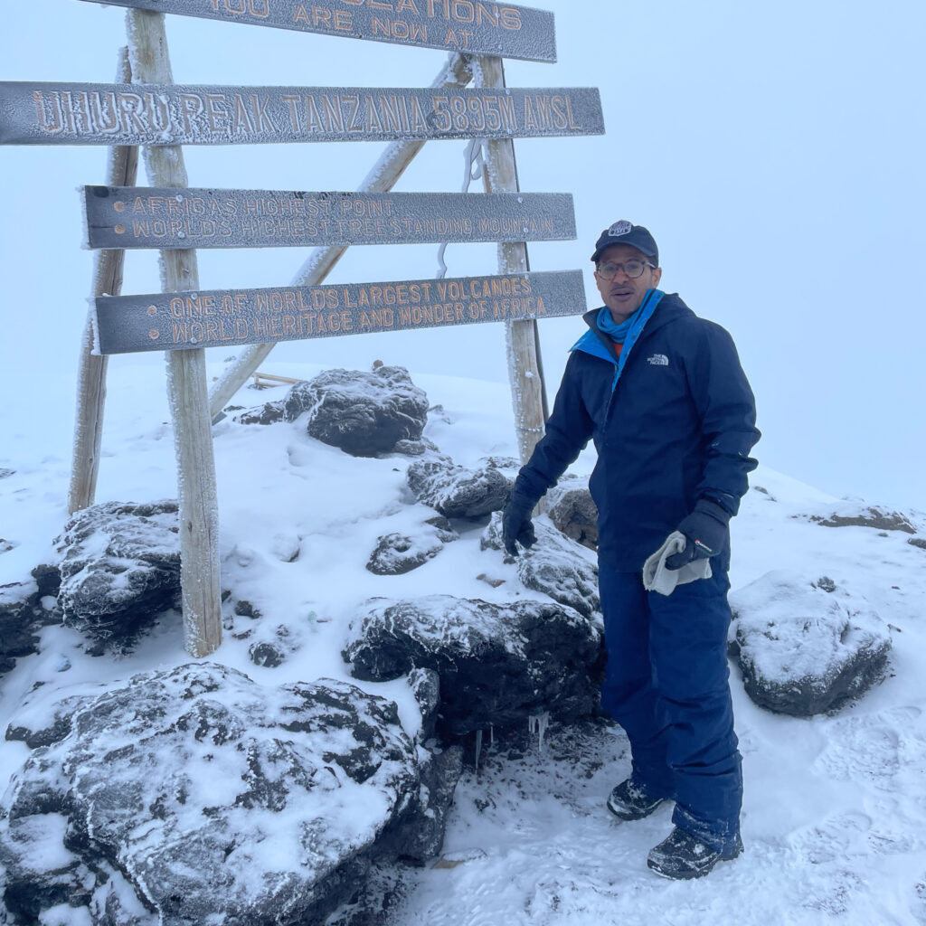 Hamoud Almutairi standing on the summit of Mount Kilimanjaro in frosty conditions, surrounded by snow and ice, celebrating his achievement and transformative climb.