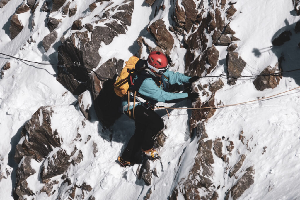 A Life Happens Outdoors climber carefully crossing the Grand Couloir on Mont Blanc in frozen early morning conditions under the supervision of an IFMGA guide.