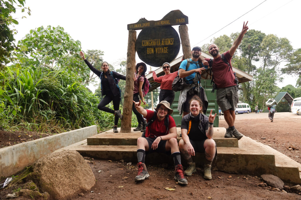 Life Happens Outdoors climbers celebrate at Mweka Gate after successfully summiting Mount Kilimanjaro, marking the end of their incredible journey.