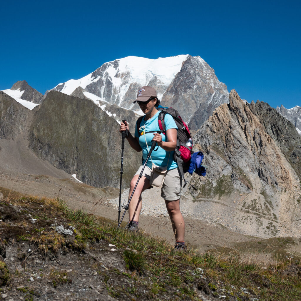 Life Happens Outdoors community member hiking the Tour du Mont Blanc with the Mont Blanc massif rising behind under clear blue skies.