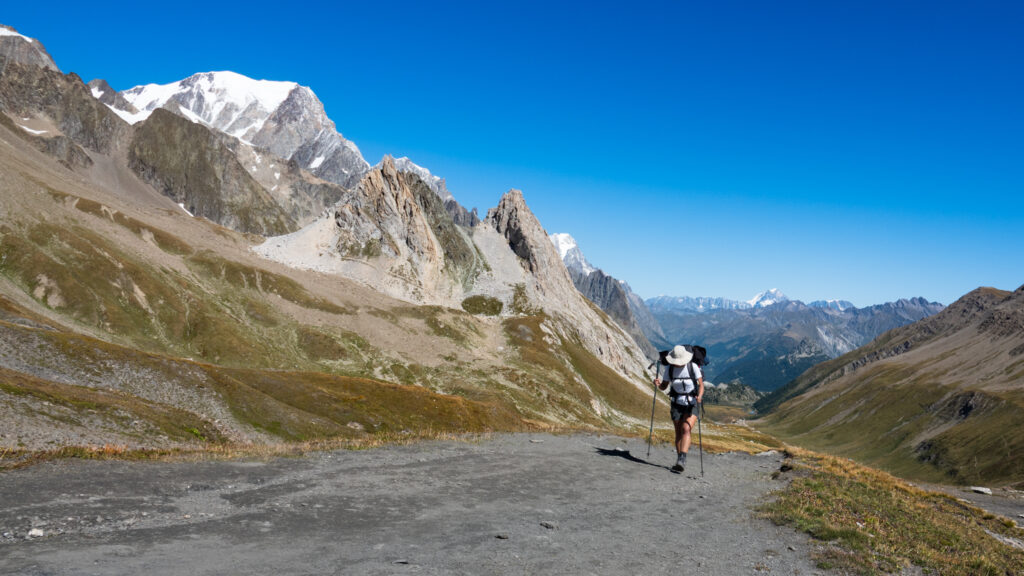 Life Happens Outdoors community member trekking the Tour du Mont Blanc with the Mont Blanc summit visible under clear blue skies.
