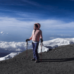 Life Happens Outdoors Community member on the Kilimanjaro crater rim with glaciers and blue sky during a clear summit day