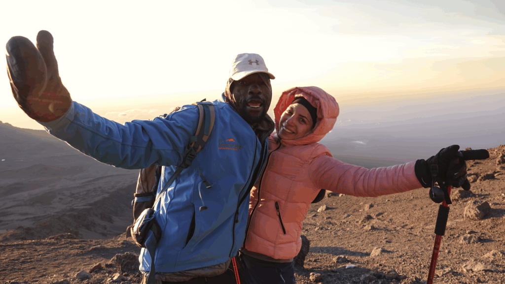 HO lead guide Emmanuel Aceno and a Life Happens Outdoors Community member celebrating sunrise on summit night during the Kilimanjaro climb