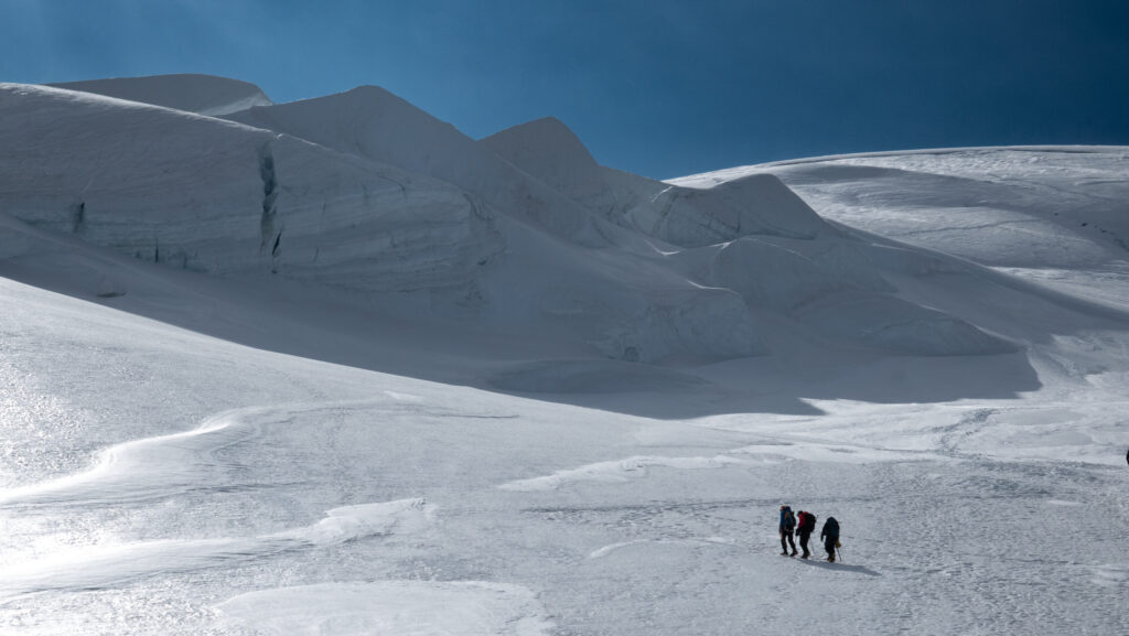 Life Happens Outdoors climbers on the Dome du Gouter switchbacks, with the Seracs Glacier above, on the way to the summit of Mont Blanc.