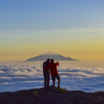 Two Life Happens Outdoors community members at Shira Camp on Kilimanjaro at sunset above a sea of clouds looking toward Mount Meru