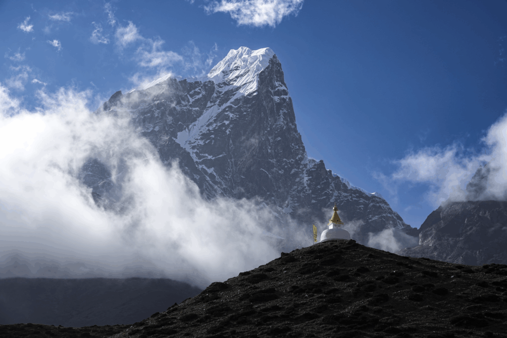 Buddhist stupa on a hill above Dingboche with the high Himalaya mountains behind on the Everest Base Camp trail in Nepal.