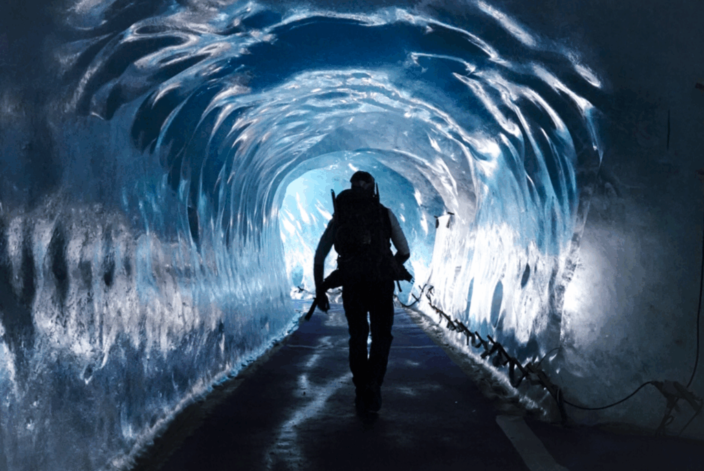 Life Happens Outdoors climber walking out of an ice cave in Chamonix, symbolizing resilience built through discomfort.