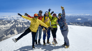 Life Happens Outdoors community members celebrating on the summit of Mont Blanc in clear blue sky weather.