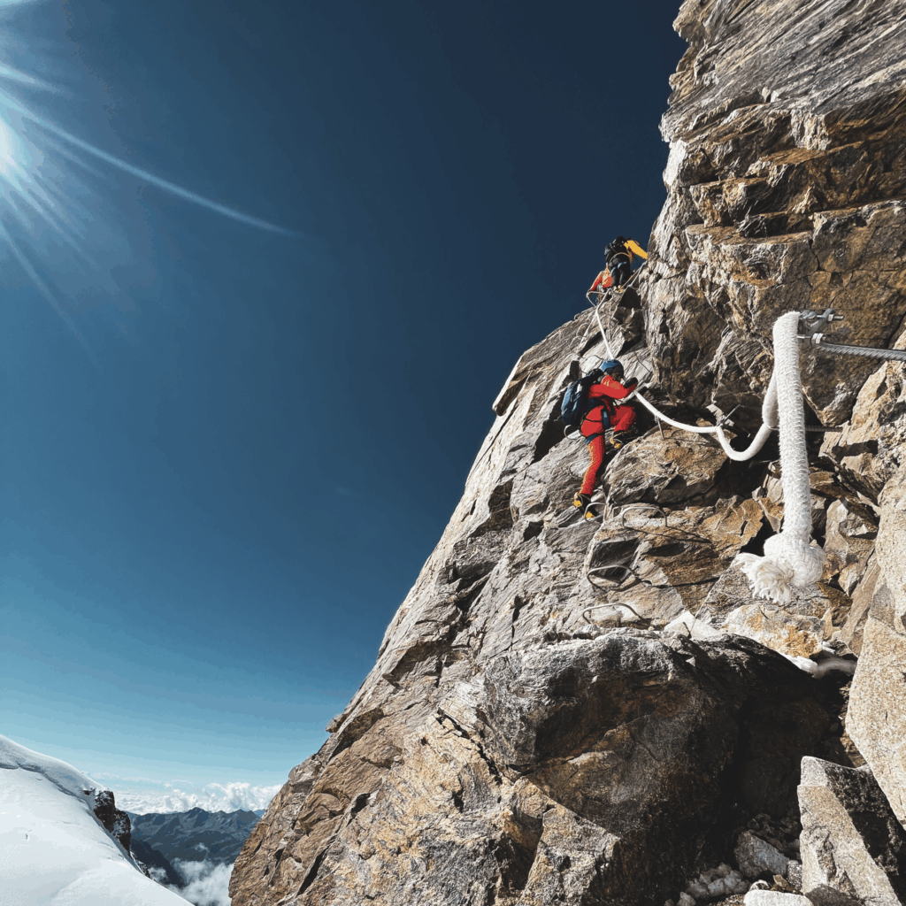 Life Happens Outdoors climbers on a via ferrata in the Monte Rosa massif above a glacier, capturing teamwork, exposure, and shared challenge