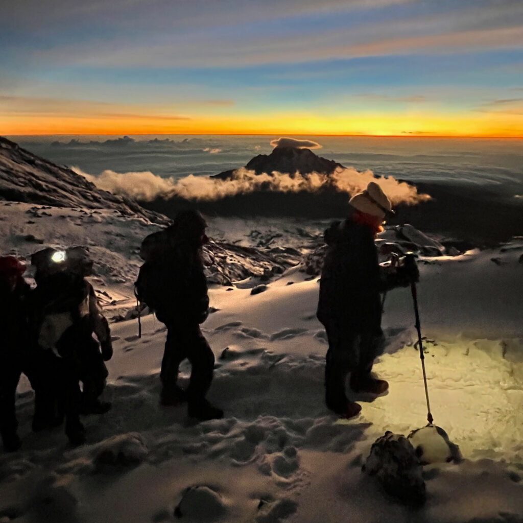 Sunrise on Kilimanjaro during summit night as the sky brightens and the team keeps moving steadily