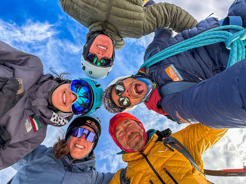 Life Happens Outdoors climbers standing in a circle and looking down at the camera outdoors.