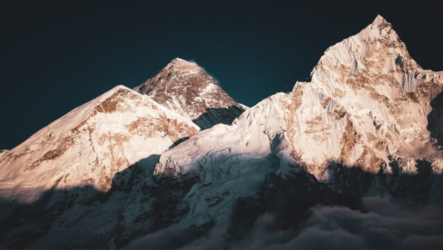 Sunrise light on snow covered Himalayan mountains above clouds in Nepal