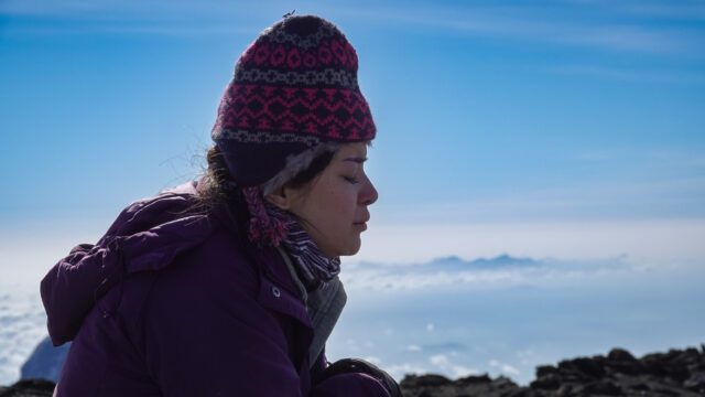 Traveler practicing calm breathing on a snowy mountain during a big adventure