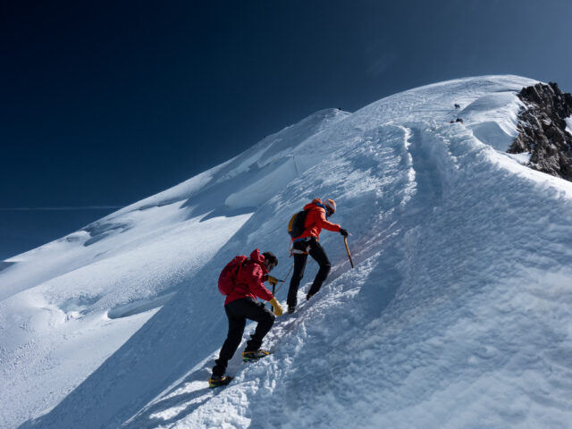 Climbers ascending a steep snowy ridge during a guided alpine climb