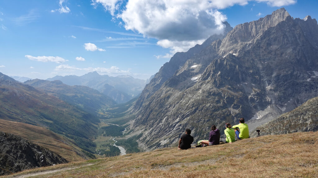 Small group of trekkers resting above the Italian Val Ferret on the Grand Col Ferret stage of the Tour du Mont Blanc