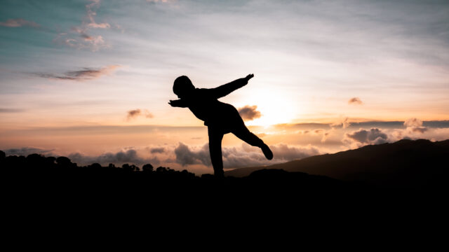 Silhouette of a person balancing at sunset above the clouds on Mount Kilimanjaro.